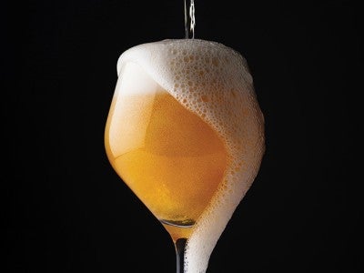 Photo of beer being poured into a glass and overflowing