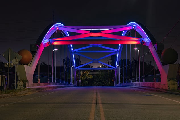 Bridge lit up at night over highway