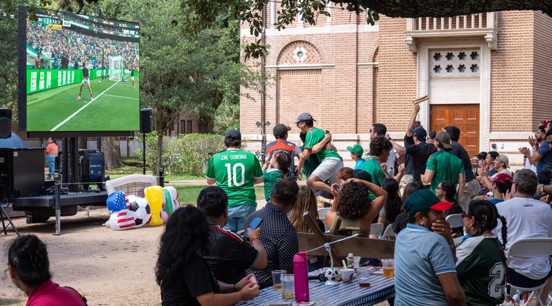 Photo of fans in Valhalla courtyard cheering at the game on the big screen
