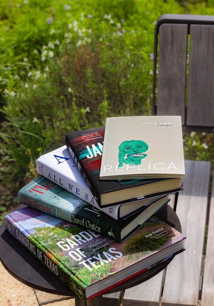 Stack of featured alumni books photographed in the academic quad