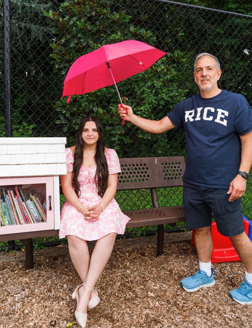 Photo of Lucia Noto during the photoshoot with her father holding an umbrella over her
