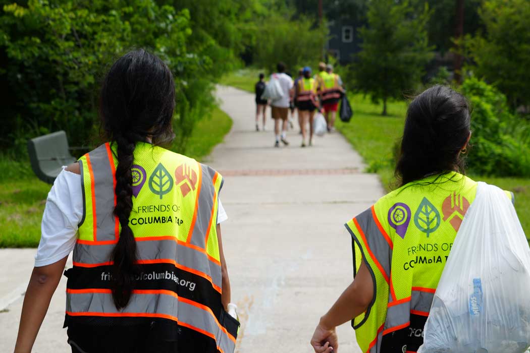 Photo of students carrying trash bags while cleaning a nature trail