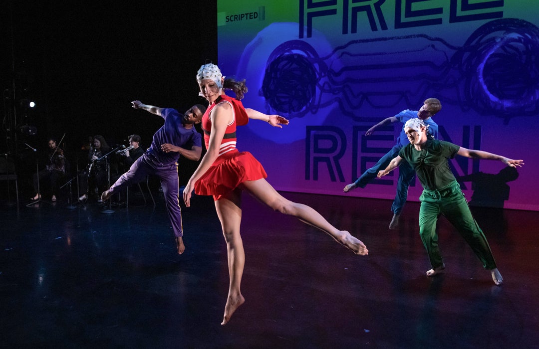Photo of dancers dancing while wearing imaging equipment with 4 musicians to the left of the stage