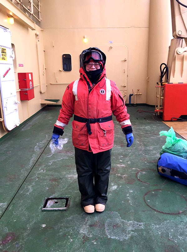 Welzenbach on the deck of the Palmer in a flotation coat and hip waders waiting to board an inflatable boat called a Zodiac.