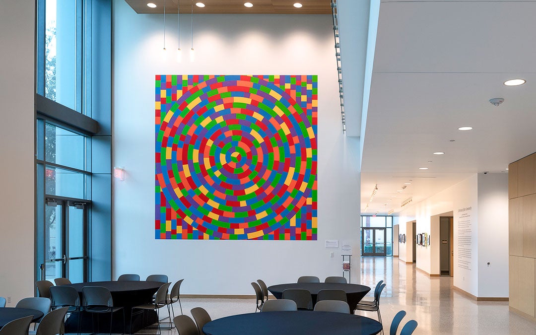 Photo of Climate Parliament with hybrid speaker-lights suspended from the ceiling of an enclosed exterior passageway 