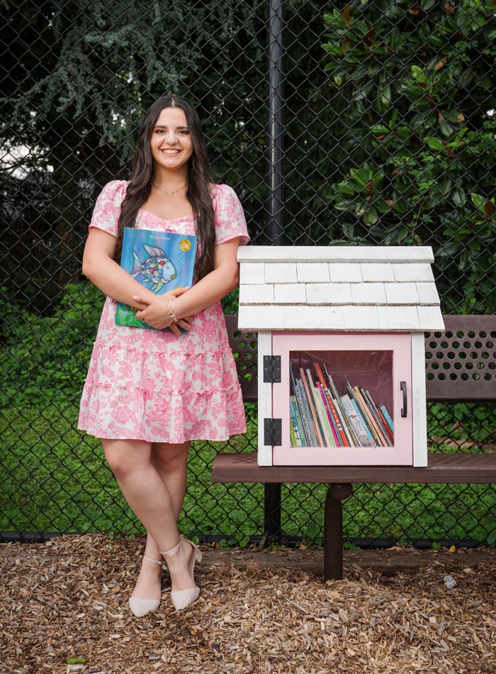 Photo of student Lucia Noto standing next to a Little Library