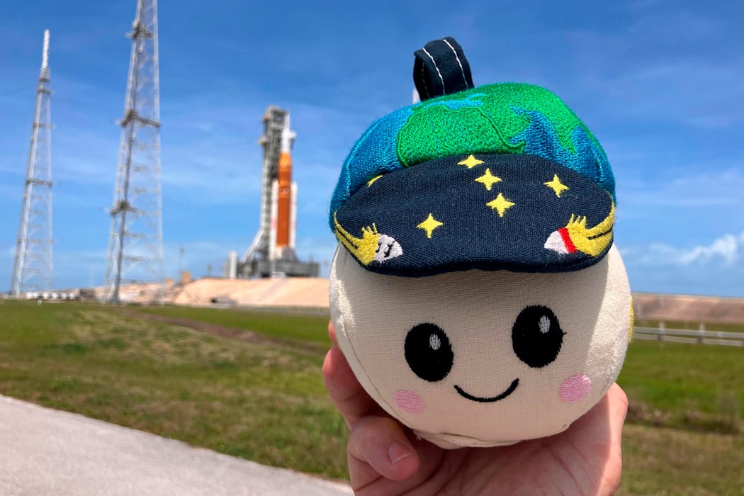 Close-up photo of the moon-shaped plushie being held up in front of the launch site