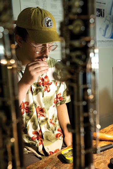 Student Jacob Duff tests out the pitch of a reed in progress, which is called “crowing the reed.”