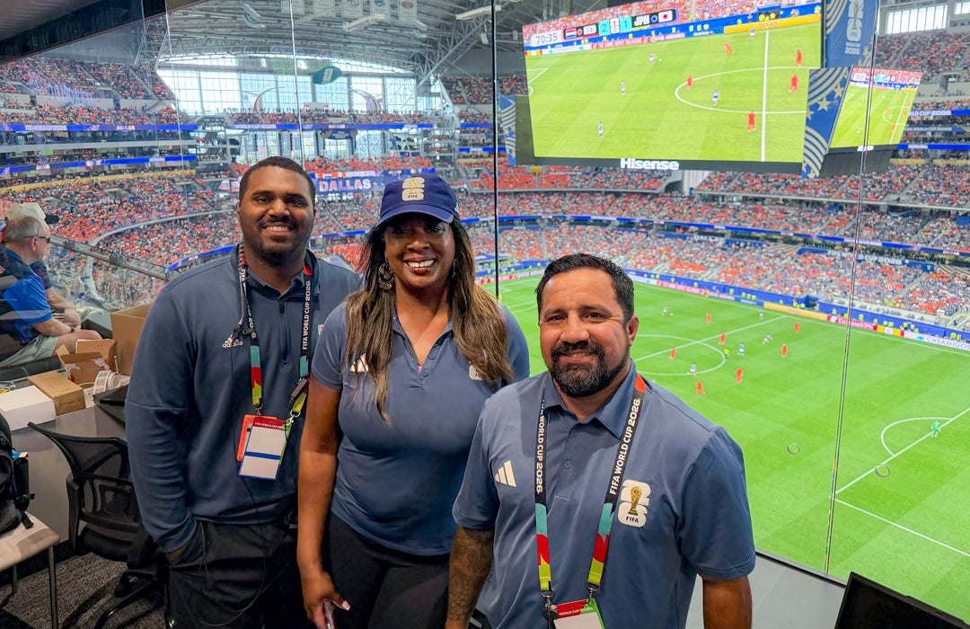 Photo of Rice alums together with a view of the soccer field in Dallas