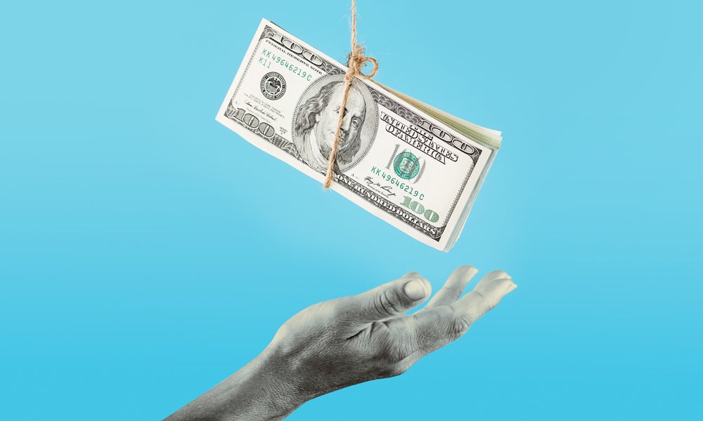 Hand trying to grasp hundred dollar bills