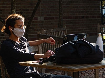 Rice student wearing mask sitting at table outside