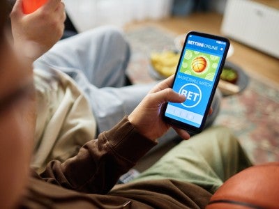 Photo of a person looking at a sports betting app on their cellphone