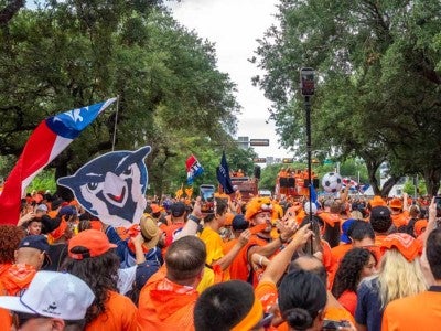 Soccer fans in a sea of orange marching past campus wearing orange Netherlands gear