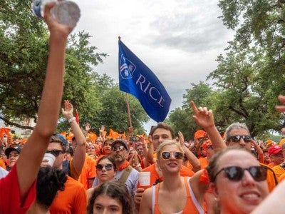 Photo of marchers wearing orange and holding Rice flag