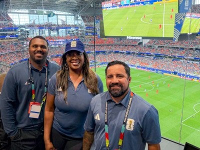 Photo of Rice alums together with a view of the soccer field in Dallas
